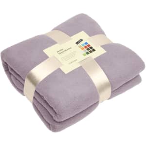 A folded purple fleece blanket, secured with a ribbon and label, displaying soft fabric texture.