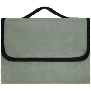 A green picnic blanket with a black edge and a handle for carrying. It has a soft, plush texture.