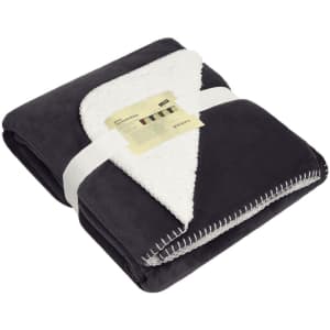 A folded black and white blanket with a soft, fluffy interior, neatly tied with a ribbon and featuring a label.