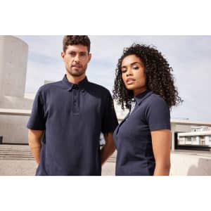 Two models wearing navy plain polo shirts outdoors, standing side by side against a modern architectural backdrop.