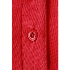 A close-up of a red ladies polo shirt featuring a button and textured fabric. The shirt has a logo on the fabric.