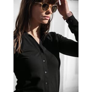 A black polo shirt is worn by a woman with sunglasses, featuring a buttoned front and long sleeves.