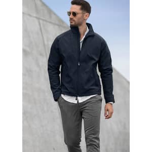 A man wearing a navy soft shell jacket and grey trousers, with sunglasses and a white shirt underneath.