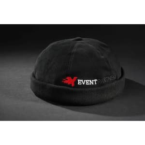 A black 6 panel chef cap with a folded brim and a logo featuring red text on the front.