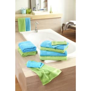 A collection of blue and green bath towels arranged on a wooden surface near a bathtub.