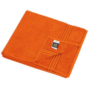 An orange towel folded neatly, featuring a textured pattern and a label on one corner.