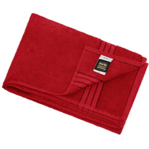 A red bath sheet folded neatly, featuring a tag and a striped design on one corner.