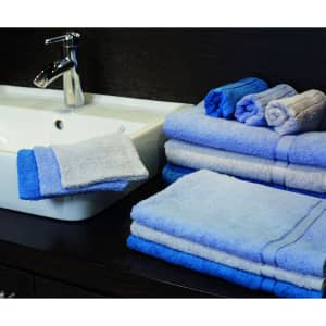 A collection of blue and light blue towels neatly arranged on a counter beside a sink.