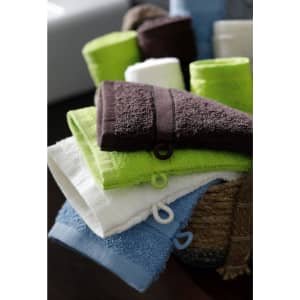 A collection of towels in various colours, including green, white, brown, and blue, neatly arranged in a basket.