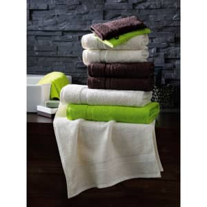A stacked arrangement of towels in white, brown, and green, with varying sizes and textures, placed on a dark surface.