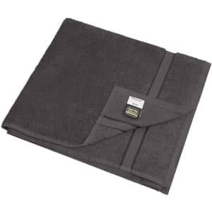 A dark grey bath towel folded neatly, featuring a tag and a textured surface.