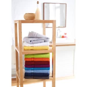 A display of neatly stacked bath towels in various colours, including grey, yellow, red, and blue, on a wooden shelf.