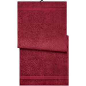 A burgundy bath sheet displayed flat, featuring a textured design and a subtle stripe detail at the edges.