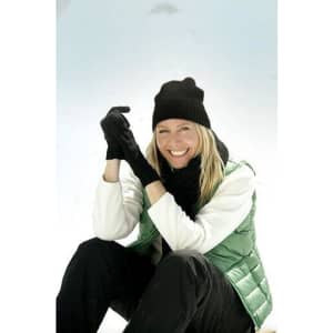 A woman wearing a black beanie and gloves, seated on snow, dressed in a green vest and black pants.