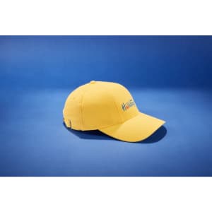 A yellow six-panel cap featuring a logo, displayed against a blue background.