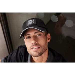 A black 6 Panel Raver Sandwich Cap with a logo, featuring a grey trim and an adjustable strap at the back.