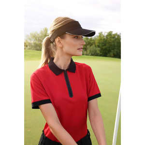 A sporty red polo shirt paired with a black Sandwich Sunvisor, worn by a woman on a golf course.