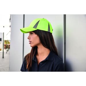 A bright yellow safety cap with reflective accents worn by a woman, set against an urban backdrop.