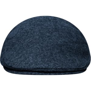 A Dandy Cap in dark blue with a herringbone pattern, featuring a round shape and a soft fabric.
