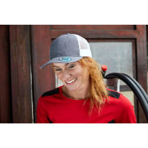 A grey and white 6 Panel Mesh Trucker cap is worn by a smiling woman with red hair, dressed in a red top.