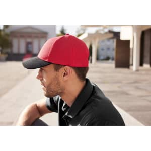 A red and black six-panel mesh cap worn by a man, set against an outdoor background.