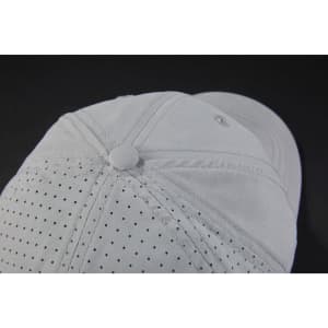 A light grey cap with laser cut holes for ventilation and a metal button on top, featuring a logo.