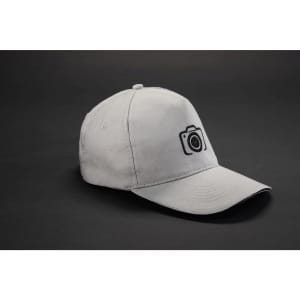 A grey 5 Panel Promo Sandwich Cap with a camera logo on the front, set against a dark background.