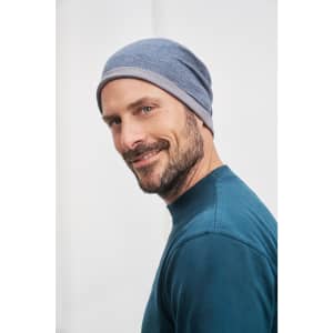 A grey beanie worn by a man with a beard, smiling while looking sideways. It features a simple logo.