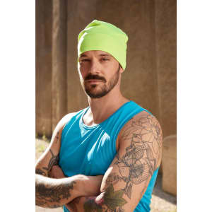 A bright yellow running beanie worn by a man with tattoos, dressed in a blue tank top, posing outdoors.