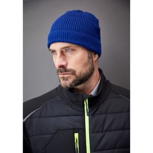 A blue ribbed beanie worn by a man in a black jacket, featuring a simple design and a logo.