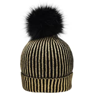 A black and gold metallic beanie with a fluffy black pom-pom on top. Features vertical stripes and a brand logo.