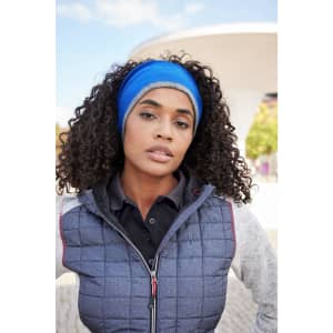 A reversible headband in blue worn by a woman with curly hair, set against an outdoor background.