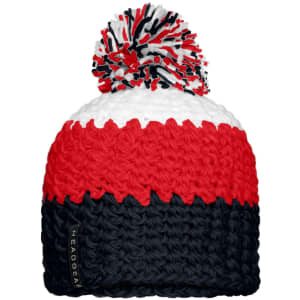 A knitted beanie in red, white, and navy with a large pompon on top and a logo tag on the side.