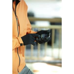 A person wearing black touch-screen knitted gloves uses a mobile device while dressed in an orange jacket.