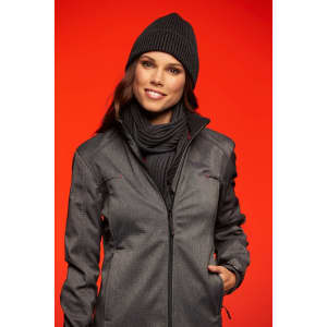 A woman wears a ribbed black scarf and matching beanie, paired with a grey jacket against a vibrant orange background.