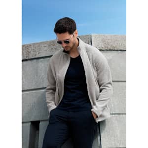 A polar fleece jacket in beige, featuring a stand-up collar and a brand logo, worn by a man.
