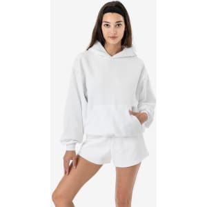 A white mineral wash fleece wide hoodie with a front pocket, styled with shorts and featuring a logo.