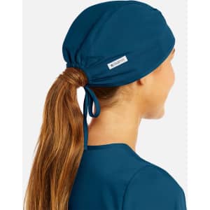 A unisex scrub cap in deep teal, featuring a tied design and a small branded label.