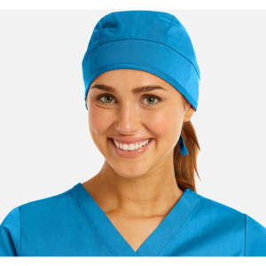 A blue unisex scrub cap worn by a smiling individual, paired with a matching scrub top.