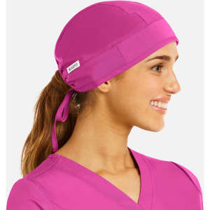A unisex scrub cap in vibrant pink, featuring a tied back design and a small branding label.