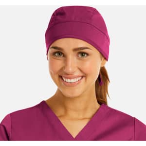 A unisex scrub cap in a vibrant purple, worn by a smiling individual with brown hair tied back.