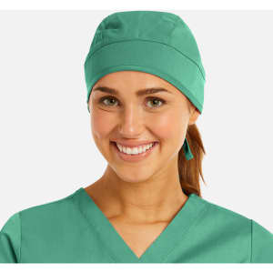 A unisex scrub cap in teal worn by a smiling individual. The cap has a simple design and fits comfortably.