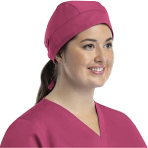 A unisex scrub cap in vibrant pink, featuring buttons, worn by a smiling woman.