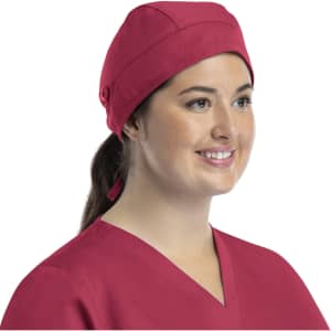 A unisex scrub cap in a vibrant pink colour, featuring buttons and a structured design, worn by a smiling individual.