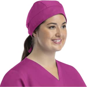 A unisex scrub cap in bright pink with buttons, worn by a woman smiling. It features a stylish design.