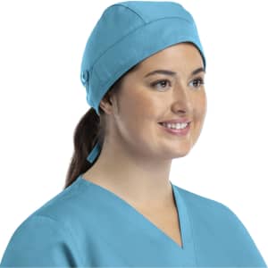 A unisex scrub cap in light blue with buttons, worn by a person with a ponytail, smiling.