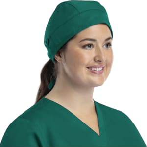 A green unisex scrub cap with buttons, worn by a smiling woman in a medical uniform.