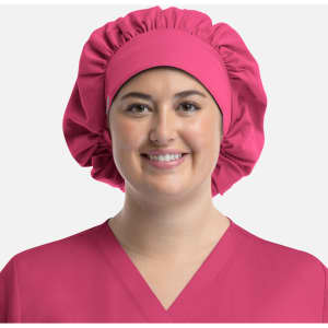 A unisex bouffant scrub cap in vibrant pink, featuring a gathered design, worn by a smiling person.