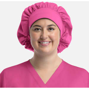 A pink bouffant cap worn by a smiling model, paired with a matching pink uniform top. The cap features a gathered design.