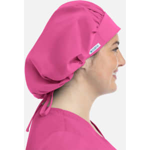 A unisex bouffant cap in bright pink, worn by a smiling person, featuring a logo on the side.